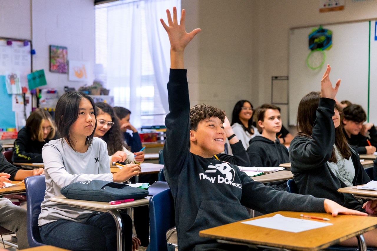 A student eagerly raises his hand during class.